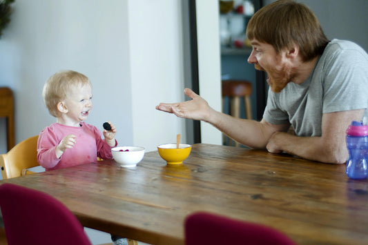 Man sat with child at the dinner table giving her praise